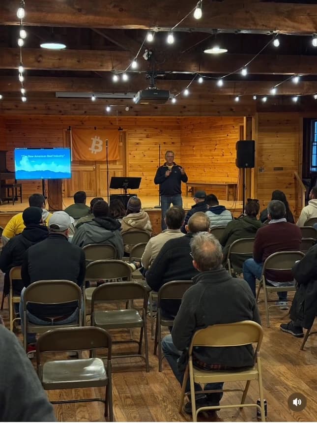 Speaker presenting to an engaged audience in the Camp Nakamoto lodge